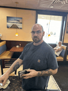 a man in a carhartt shirt is holding a wallet and a twenty dollar bill