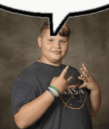 a boy wearing a nasa t-shirt makes a peace sign