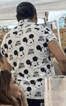 a man wearing a mickey mouse shirt is standing in a room .