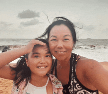 a woman and a little girl are posing for a picture and the little girl is wearing a shirt that says hawaii