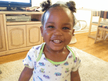 a little girl is smiling in front of a tv