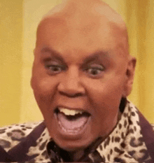 a bald man wearing a leopard print shirt and a purple jacket is making a funny face .