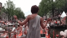 a woman in a white dress is standing in front of a crowd of people on boats .