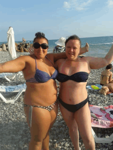 two women in bikinis are posing for a picture on the beach