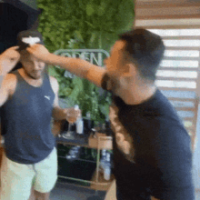 a man wearing a black tank top is being punched in the face by another man