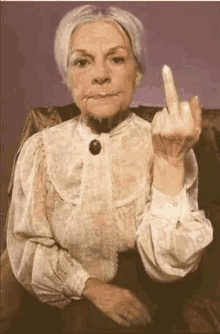 an old woman is sitting in a chair giving the middle finger .