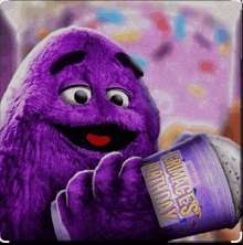 a purple cartoon character is holding a cup that says primates birthday on it