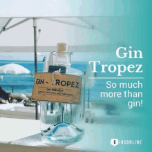 a bottle of gin tropez sits on a table in front of a beach