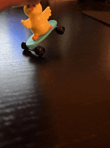 a toy duck riding a blue skateboard on a table