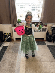 a little girl in a frozen costume is holding a pink bucket