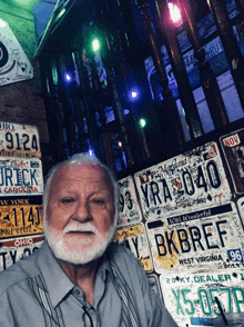 a man sitting in front of a wall of license plates one of which says bkbret