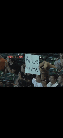 a group of people sitting in a stadium holding a sign that says " altuver time "