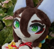 a stuffed animal with green eyes and brown hair is sitting in front of a plant .