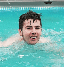 a man is swimming in a pool and smiling for the camera