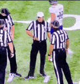 a group of referees standing on a field with one wearing a jersey that says ' u ' on it