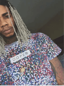 a man with dreadlocks is wearing a shirt that says dope on it