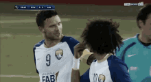 a soccer player with the number 9 on his jersey talks to another player