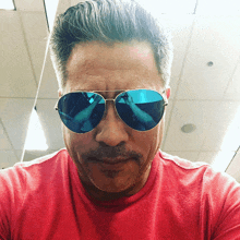 a man wearing a red shirt and a pair of blue aviator sunglasses