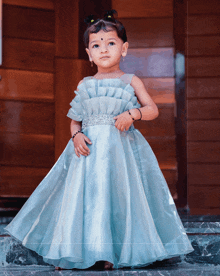 a little girl in a blue dress is standing on a set of steps