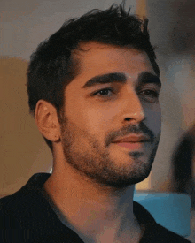 a close up of a man 's face with a beard and black shirt