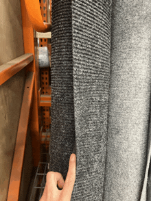 a person is pointing to a piece of gray fabric