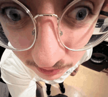 a close up of a man 's face with glasses and a t-shirt that says ' a ' on it