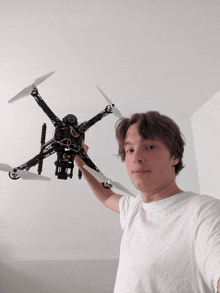 a man in a white shirt is holding up a drone with the word drone on the front