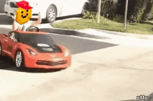 a person is driving a red toy car down the street .