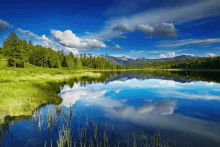 a lake with mountains in the background and clouds reflecting in the water