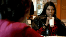 a woman is drinking a drink through a straw while sitting at a table with a plate of food .