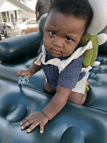 a baby in a blue shirt is crawling on an inflatable mattress