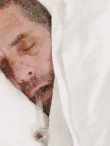 a man with a beard is laying under a white sheet