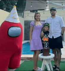 a family is posing for a picture in front of a red among us inflatable costume .