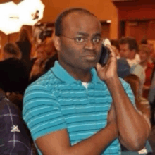 a man in a blue and white striped shirt is talking on his cell phone