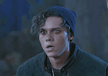 a young man with green eyes is wearing a blue hat