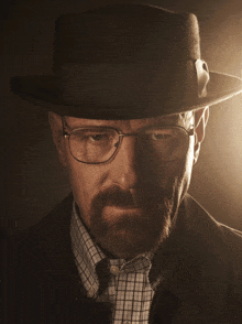 a man with a beard and glasses wearing a fedora