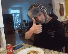 a man is giving a thumbs up in front of a plate of food and a can of coca cola