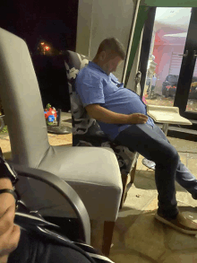 a man in a blue shirt is sitting in a chair with a large belly