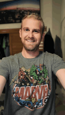 a man wearing a gray marvel t-shirt smiles for the camera