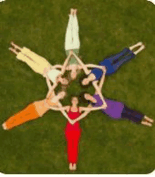 a group of people are laying in a circle on the grass .