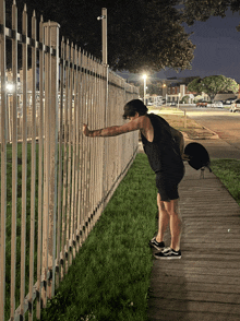 a person leaning against a fence with a hat on their head