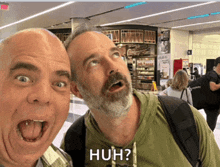 two men are posing for a picture and one has the word huh on his shirt