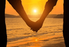 a couple is holding hands in front of a sunset .