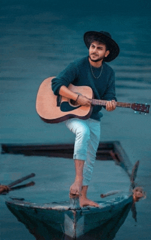 a man in a hat holds an acoustic guitar while standing on a boat