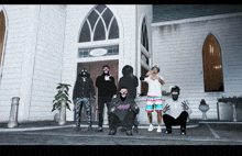 a group of masked men pose in front of a white building