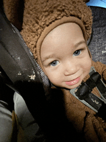 a baby wearing a brown hat and a teddy bear outfit