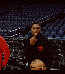 a man holding a spalding basketball in a stadium