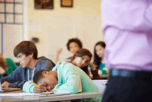 a girl is sleeping in a classroom while a teacher looks on