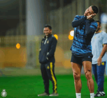 a soccer player is standing on a field with his hands on his head