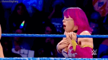 a woman with pink hair is in a wrestling ring with a w logo on the ropes